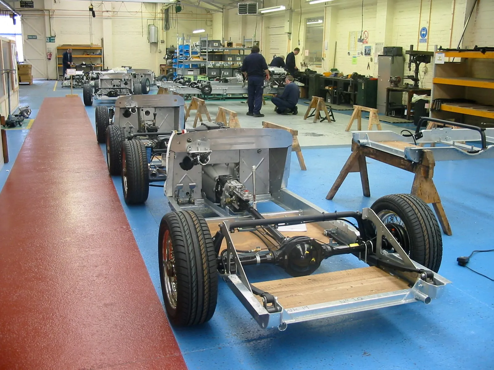 A bare chassis on wheels with a wooden floor being laid, in the chassis shop
