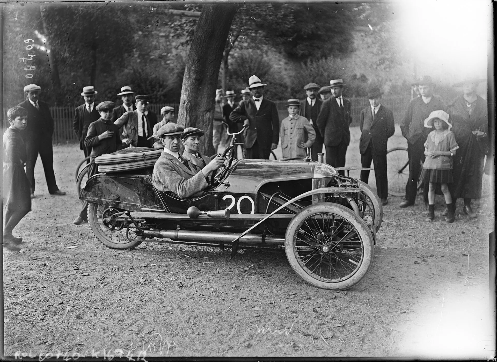 A black-and-white press photograph of a driver seated in a Morgan cyclecar on the Circuit de la Sarthe, August 1920, with spectators behind