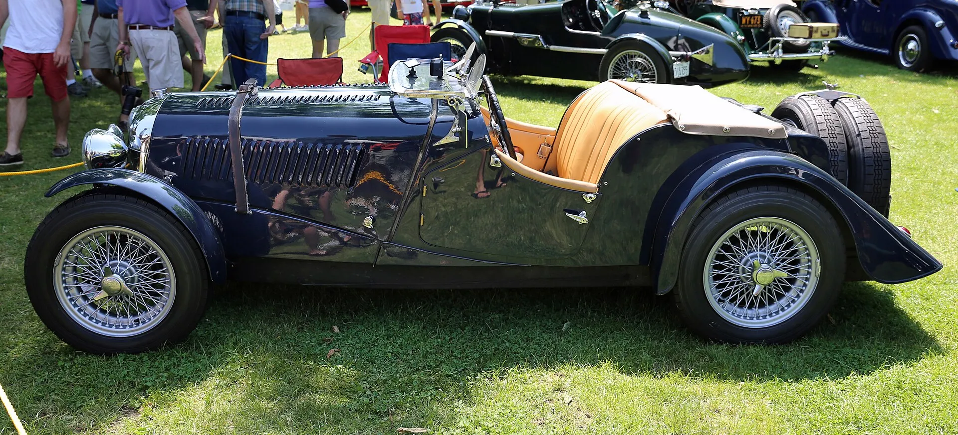 A green 1953 Morgan Plus 4 Competition with a flat radiator at a concours, side view