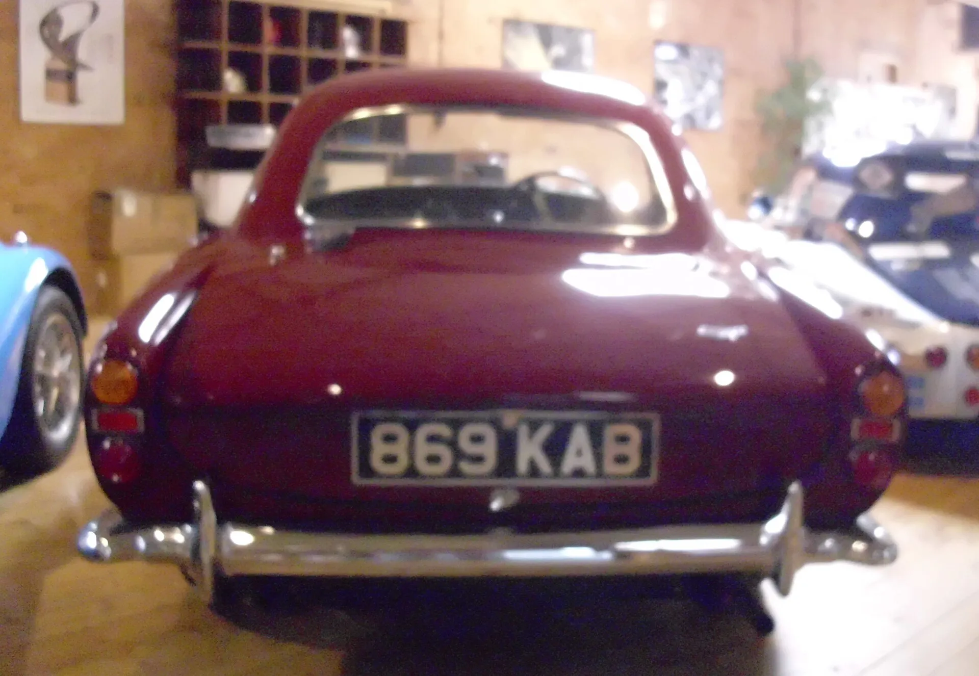 The rear of a maroon glass-fibre Morgan Plus 4 Plus coupé, registration 869 KAB, in a museum